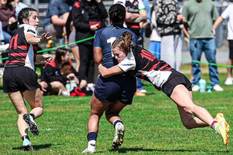 Women's rugby player for Abbotsford tackling her opponent.